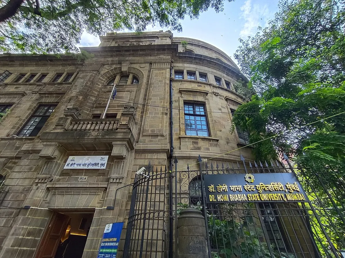 The heritage stone building of Dr. Homi Bhabha State University in Mumbai, seen from the street gate.